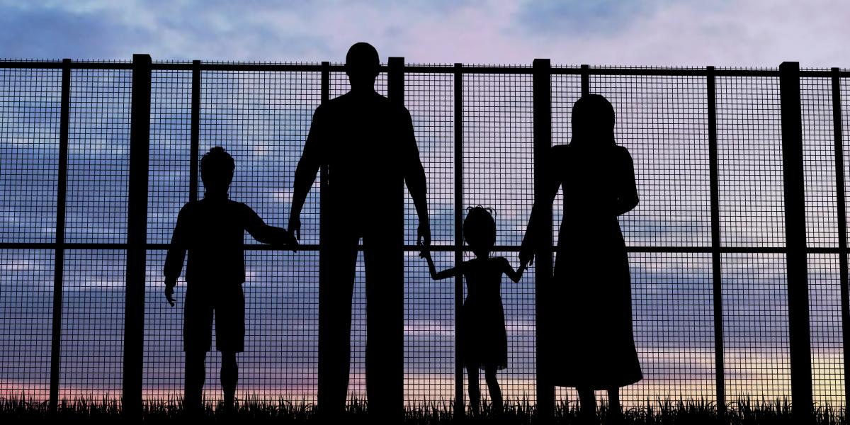 World refugee day - family waiting at a border fence.